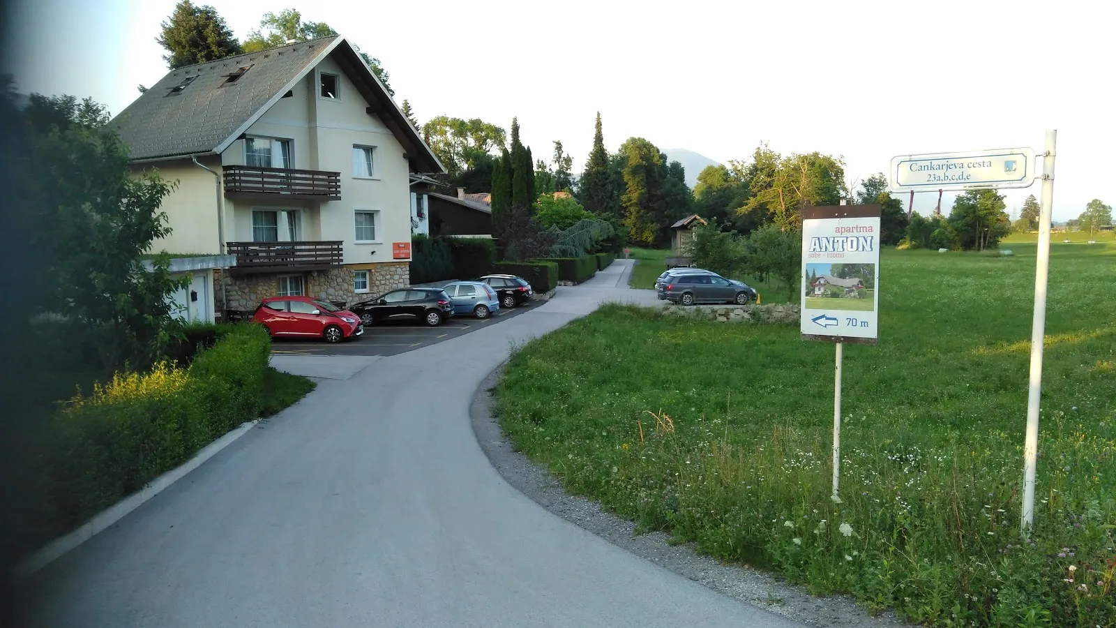Hiša z balkoni na Cankarjevi cesti, pred njo parkirani avtomobili in tabla z imenom